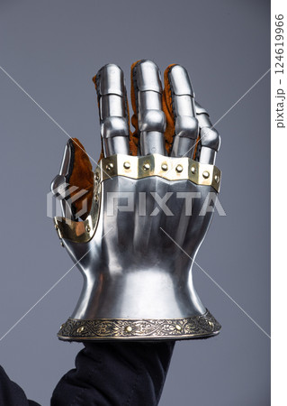 Silver Hourglass Gauntlets with Brass Details. This image shows a close-up of a pair of shiny silver hourglass gauntlets, featuring articulated fingers and brass accents along the edges and rivets. 124619966