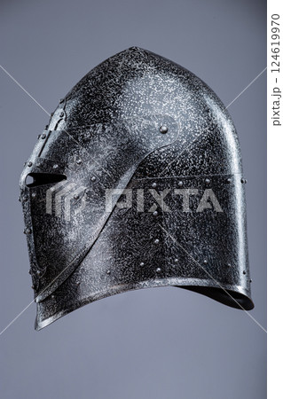 Closed Medieval Knight's Helmet with Small Perforations. This image shows a closed medieval knight's helmet, likely made of steel, with a pointed top and small perforations for ventilation and vision. Closed Medieval Knight's Helmet with Small Perforations. This image shows a closed medieval knight's helmet, likely made of steel, with a pointed top and small perforations for ventilation and vision. 124619970