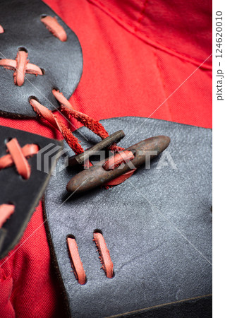 Close-up of Black and Red Leather Shoulder Armor. Detailed view of the mannequin's shoulder armor featuring black leather and contrasting red lacing. Close-up of Black and Red Leather Shoulder Armor. Detailed view of the mannequin's shoulder armor featuring black leather and contrasting red lacing. 124620010
