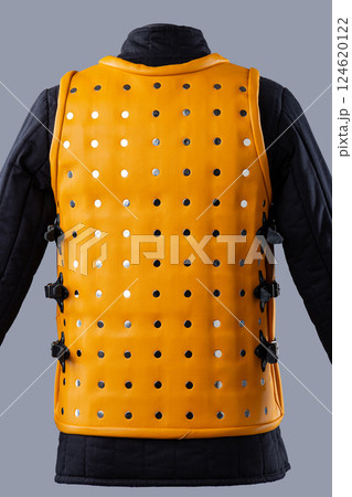 Bright Yellow Brigandine Armor with Studs. This image shows a bright yellow brigandine armor, featuring rows of silver studs and black straps with buckles on the sides. 124620122