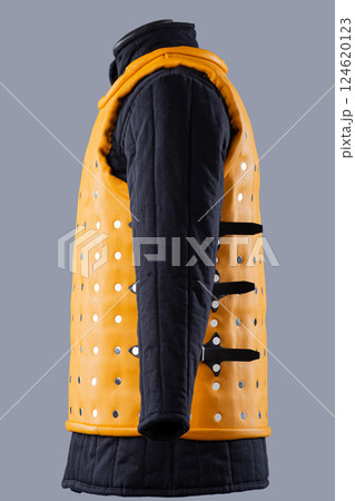 Bright Yellow Brigandine Armor with Studs. This image shows a bright yellow brigandine armor, featuring rows of silver studs and black straps with buckles on the sides. 124620123