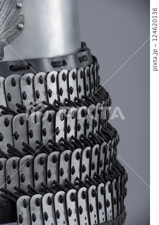 Detailed View of Silver Samurai Armor Plates and Lacing. This image provides a close-up view of silver samurai armor, showcasing the intricate overlapping plates and the dark lacing that holds them Detailed View of Silver Samurai Armor Plates and Lacing. This image provides a close-up view of silver samurai armor, showcasing the intricate overlapping plates and the dark lacing that holds them 124620136