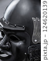 Dark Samurai Helmet with Menacing Face Mask. This image features a dark, almost black, samurai helmet with a detailed face mask displaying a fierce expression. 124620139