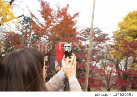 スマホで紅葉を撮影する女性 124620593