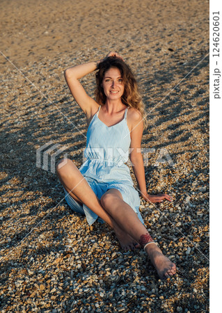 Beautiful slim fashionable woman in white summer dress on the beach by the sea Beautiful slim fashionable woman in white summer dress on the beach by the sea 124620601