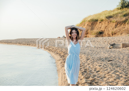 Beautiful slim fashionable woman in white summer dress on the beach by the sea Beautiful slim fashionable woman in white summer dress on the beach by the sea 124620602