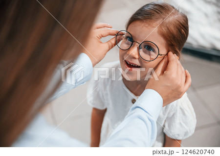 Wearing new eyewear. Woman and girl is in the glasses store Wearing new eyewear. Woman and girl is in the glasses store 124620740