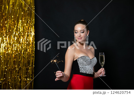 woman in evening dress with sparkler and glass of champagne for the holiday 124620754