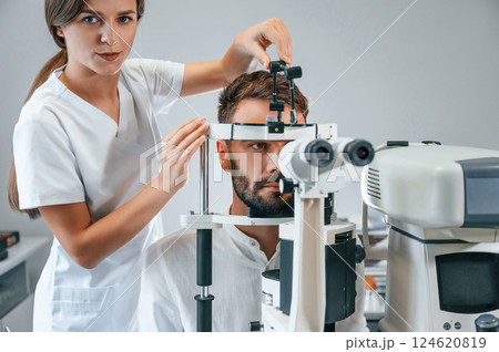 Man's vision checked by female doctor in the clinic by using special optometrist device 124620819