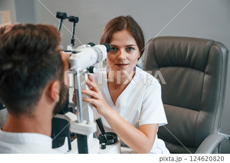 Man's vision checked by female doctor in the clinic by using special optometrist device 124620820