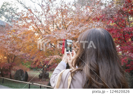 スマホで紅葉を撮影する女性 124620826