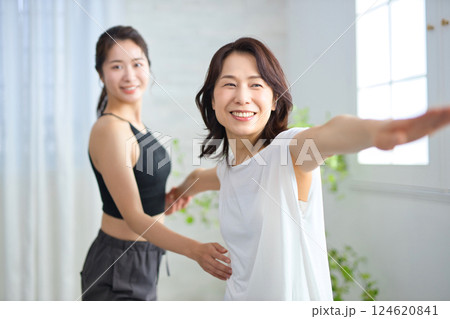 ヨガインストラクターにレッスンを受けるミドル女性 124620841