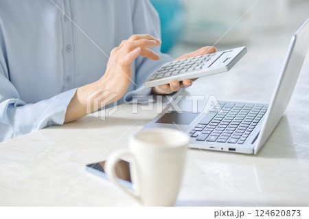 リビングでパソコンを見ながら計算機を使うミドル女性 124620873