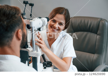 Modern technologies. Man's vision checked by female doctor in the clinic by using special optometrist device 124620890