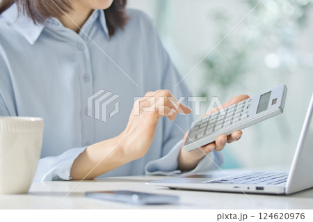 リビングでパソコンを見ながら計算機を使うミドル女性 124620976