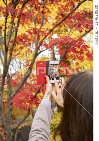 スマホで紅葉を撮影する女性 124620980