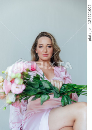 fashionable woman in light pink dress with bouquet of flowers 124621006