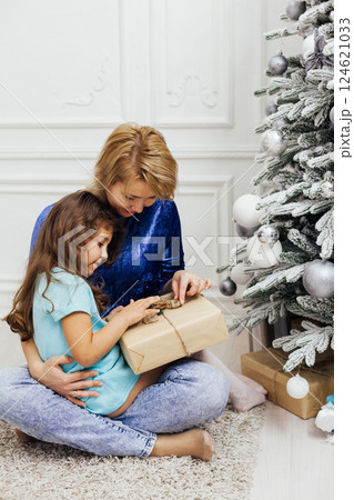 Little Curly girl and Mom at the Christmas Tree with New Year's Gifts 124621033