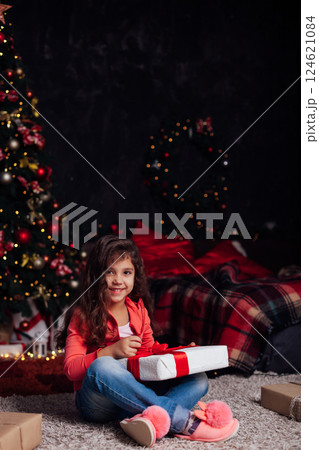 Little Curly Girl at Christmas Tree with New Year Gifts Little Curly Girl at Christmas Tree with New Year Gifts 124621084