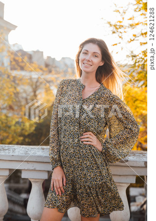 Beautiful woman in dress walking around autumn city and smiling 124621288