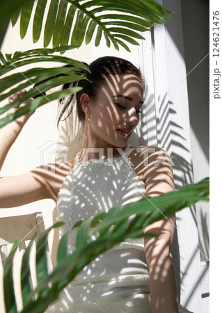 Portrait of a beautiful fashionable woman in the shade of a tropical palm tree Portrait of a beautiful fashionable woman in the shade of a tropical palm tree 124621476