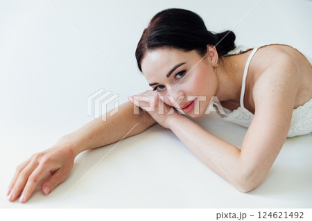 Beautiful brunette woman bride in white dress lying in bedroom 124621492