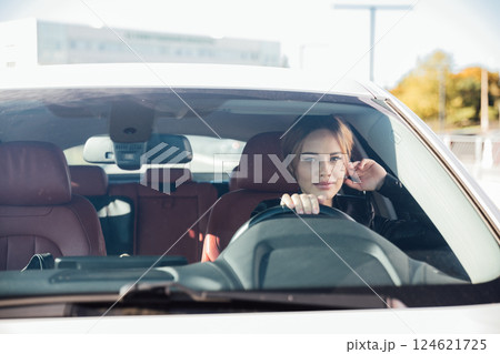 Beautiful woman driver driving a white car on the road 124621725