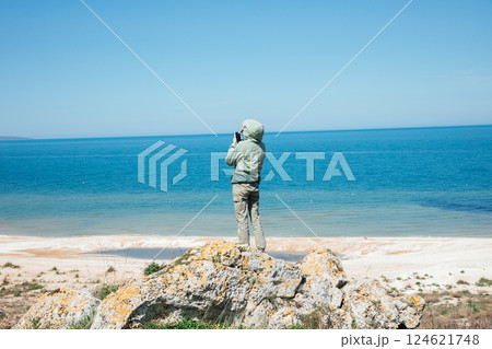 Female tourist taking pictures of the sea from the top of a mountain on her smartphone 124621748