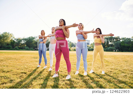 Standing and practicing. Group of women have fitness outdoors on the field together Standing and practicing. Group of women have fitness outdoors on the field together 124622903
