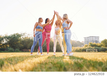 Giving high five. Group of women have fitness outdoors on the field together 124622910