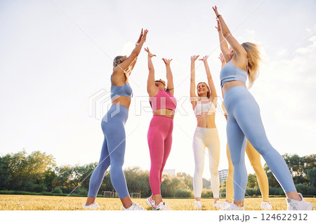Giving high five. Group of women have fitness outdoors on the field together Giving high five. Group of women have fitness outdoors on the field together 124622912