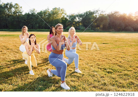 Legs workout. Group of women have fitness outdoors on the field together 124622918