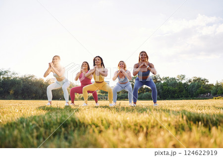 Legs workout. Group of women have fitness outdoors on the field together Legs workout. Group of women have fitness outdoors on the field together 124622919
