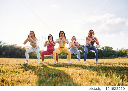 Legs workout. Group of women have fitness outdoors on the field together 124622920