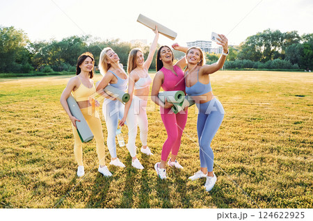 Making selfie by phone. Group of women have fitness outdoors on the field together Making selfie by phone. Group of women have fitness outdoors on the field together 124622925