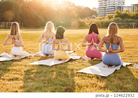Doing yoga. Group of women have fitness outdoors on the field together 124622932