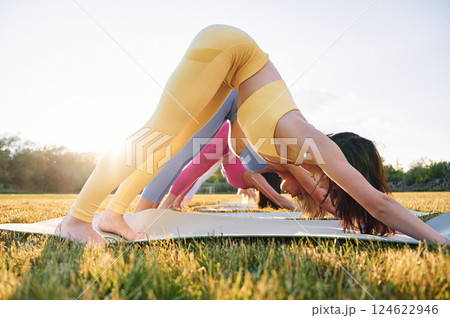 Side view. Group of women have fitness outdoors on the field together Side view. Group of women have fitness outdoors on the field together 124622946