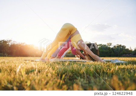 Stretching the spine. Group of women have fitness outdoors on the field together Stretching the spine. Group of women have fitness outdoors on the field together 124622948