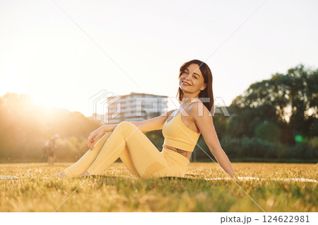 On the ground. Beautiful woman in sportive clothes doing fitness exercises outdoors on the field 124622981