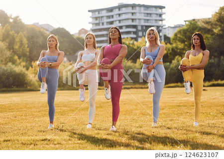 Start of the practice. Does stretch. Group of women have fitness outdoors on the field together Start of the practice. Does stretch. Group of women have fitness outdoors on the field together 124623107