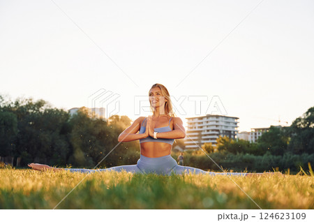 Stretching the legs. Beautiful woman in sportive clothes doing fitness exercises outdoors on the field 124623109