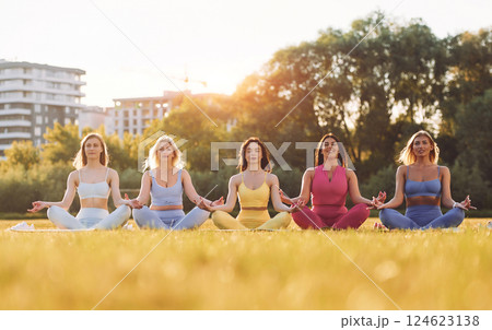 It lotus pose. Group of women have fitness outdoors on the field together 124623138