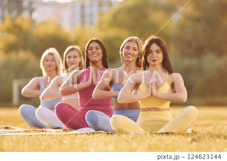 Calm meditation in lotus pose. Group of women have fitness outdoors on the field together 124623144