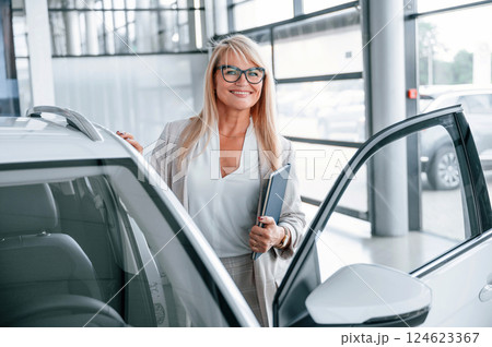 Manager is ready to help. Woman in white formal clothes is in the car dealership 124623367