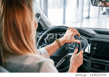 Sitting in the automobile. Woman in white formal clothes is in the car dealership 124623370