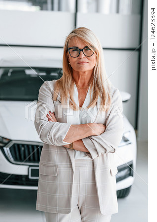 Modern automobile. Woman in white formal clothes is in the car dealership 124623394
