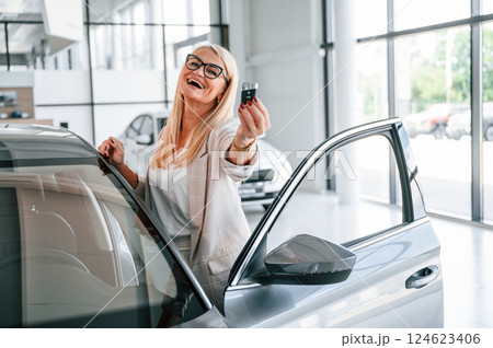 Happy positive woman in white formal clothes is in the car dealership Happy positive woman in white formal clothes is in the car dealership 124623406