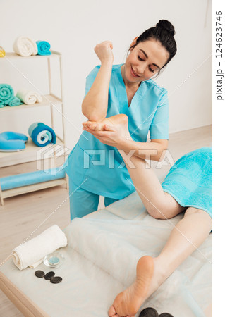 Chiropractor masseur giving foot massage to woman in spa Chiropractor masseur giving foot massage to woman in spa 124623746
