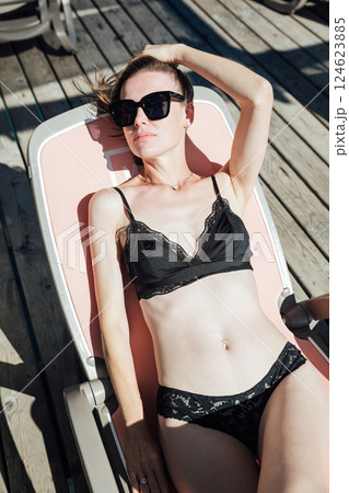 Beautiful woman in swimsuit sunbathing on the beach by the sea Beautiful woman in swimsuit sunbathing on the beach by the sea 124623885
