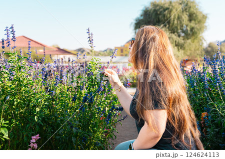 Young woman enjoying scent in blooming spring garden. The concept of youth, love, fashion and lifestyle. 124624113